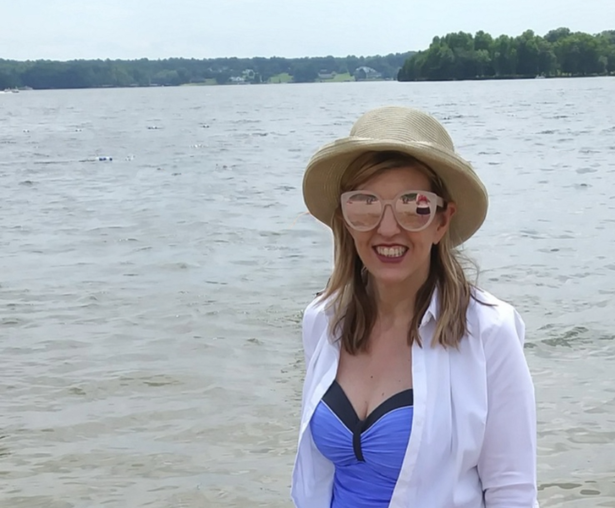 blonde lady with straw hat in front of a lake